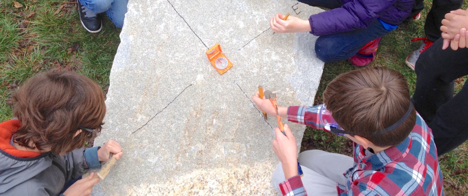 5th grade carving compass rose on granite granite boulder with compass rose